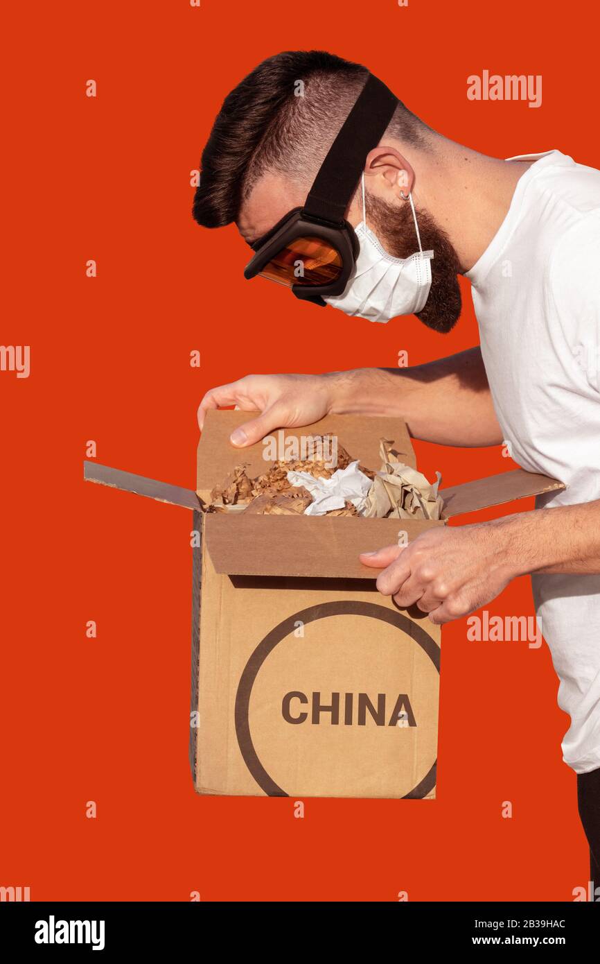 Homme en lunettes de protection et masque chirurgical déballant une boîte en carton infectée de Chine. Roman coronavirus - 2019-nCoV, chinois Wuhan virus propagation concept Banque D'Images