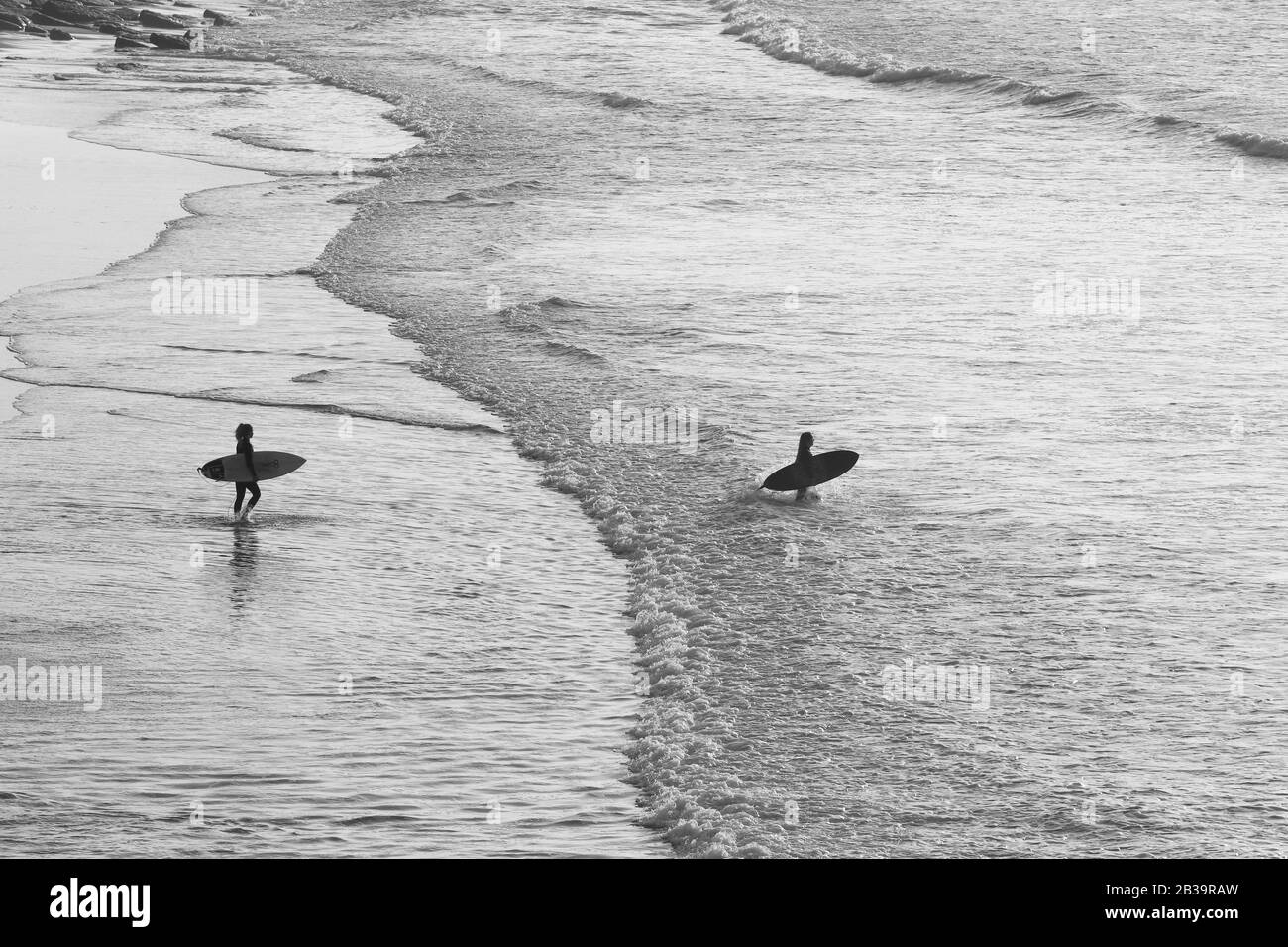 Groupe de surfeurs qui vont surfer dans l'océan au coucher du soleil. Ericeira Portugal Banque D'Images