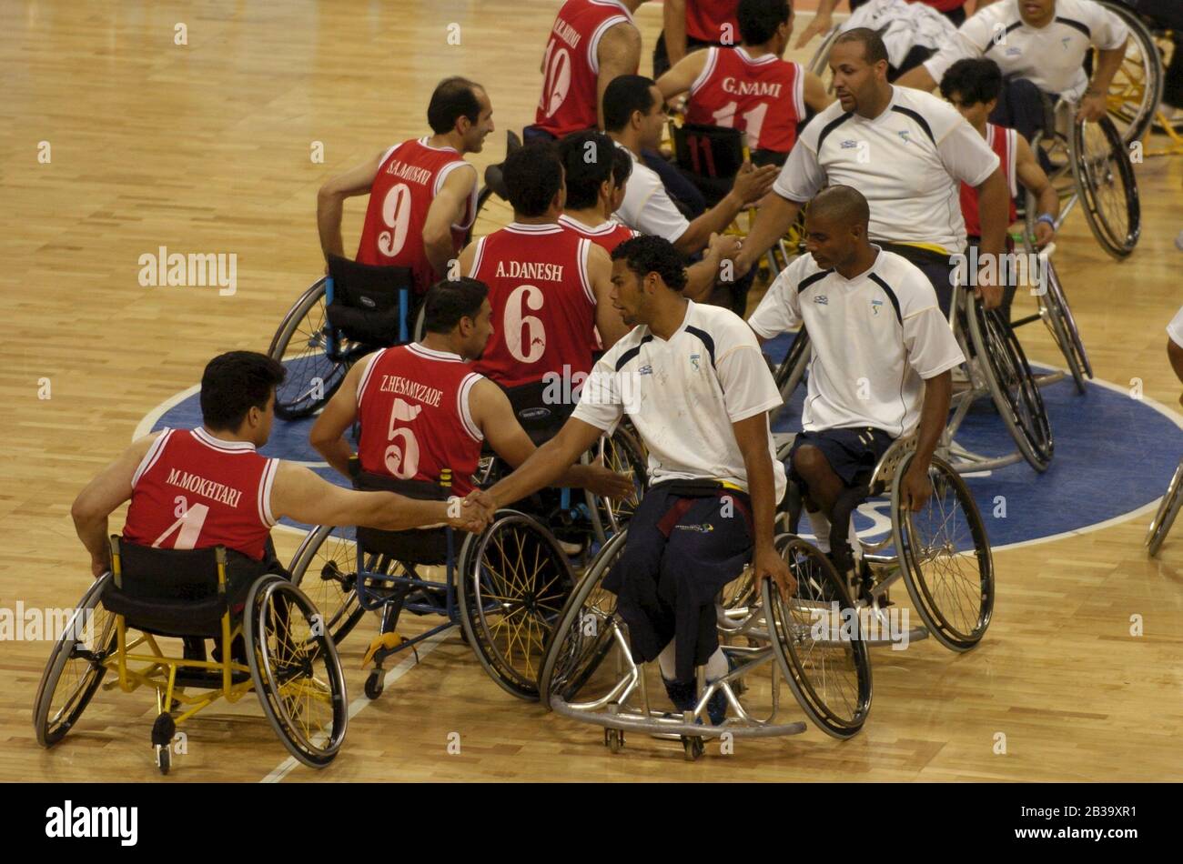 Athènes, Grèce 26 septembre 2004 : compétition paralympique entre le Brésil (blanc) et l'Iran (rouge) en basket-ball en fauteuil roulant pour hommes, avec des membres de l'équipe qui se secouent la main avec des adversaires après le match.©Bob Daemmrich Banque D'Images