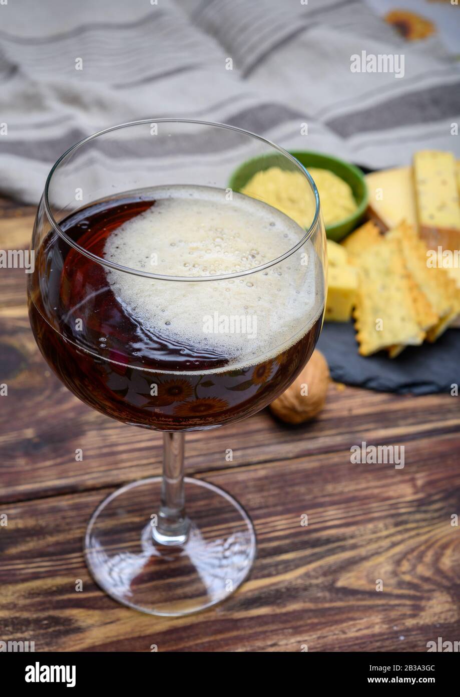 Verre de bière rouge abbatiale belge et plaque de marbre avec fromages faits par des moines à base de lait de vache avec fenugrec et graines de moutarde près Banque D'Images