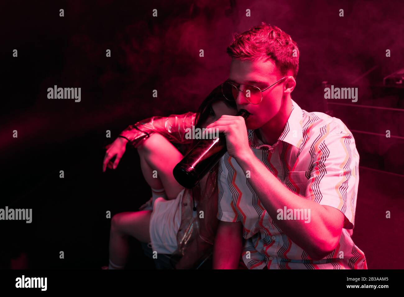 homme avec bière assis près d'une fille dans la discothèque pendant la rave Banque D'Images