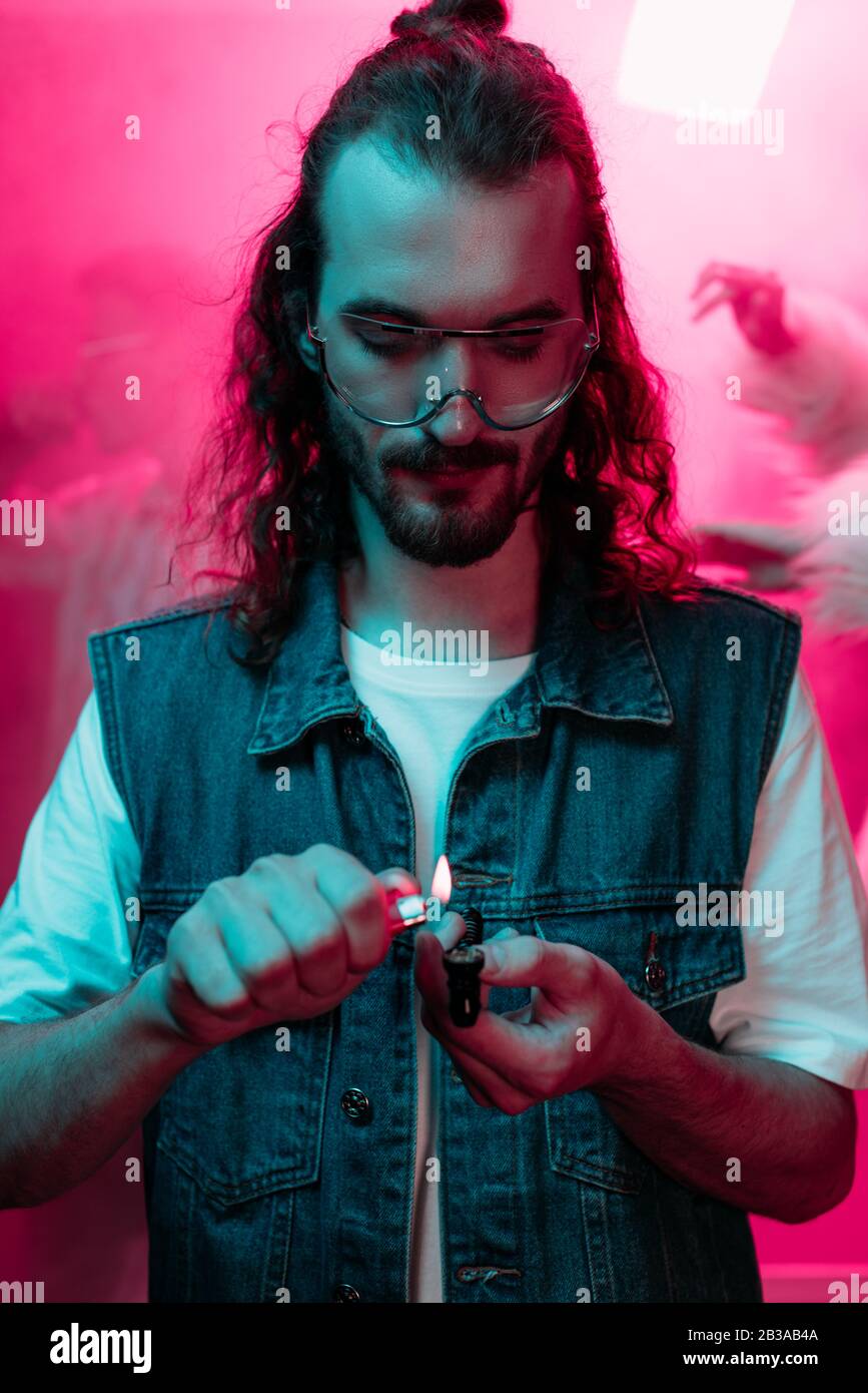 un homme qui allume un tuyau fumeur avec de la marijuana dans la discothèque Banque D'Images