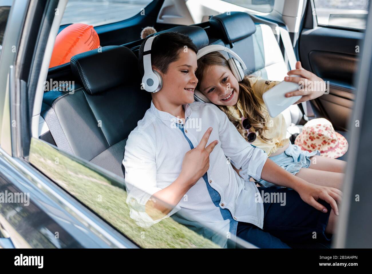 foyer sélectif de la sœur heureuse prenant selfie près de frère montrant la paix signe en voiture Banque D'Images