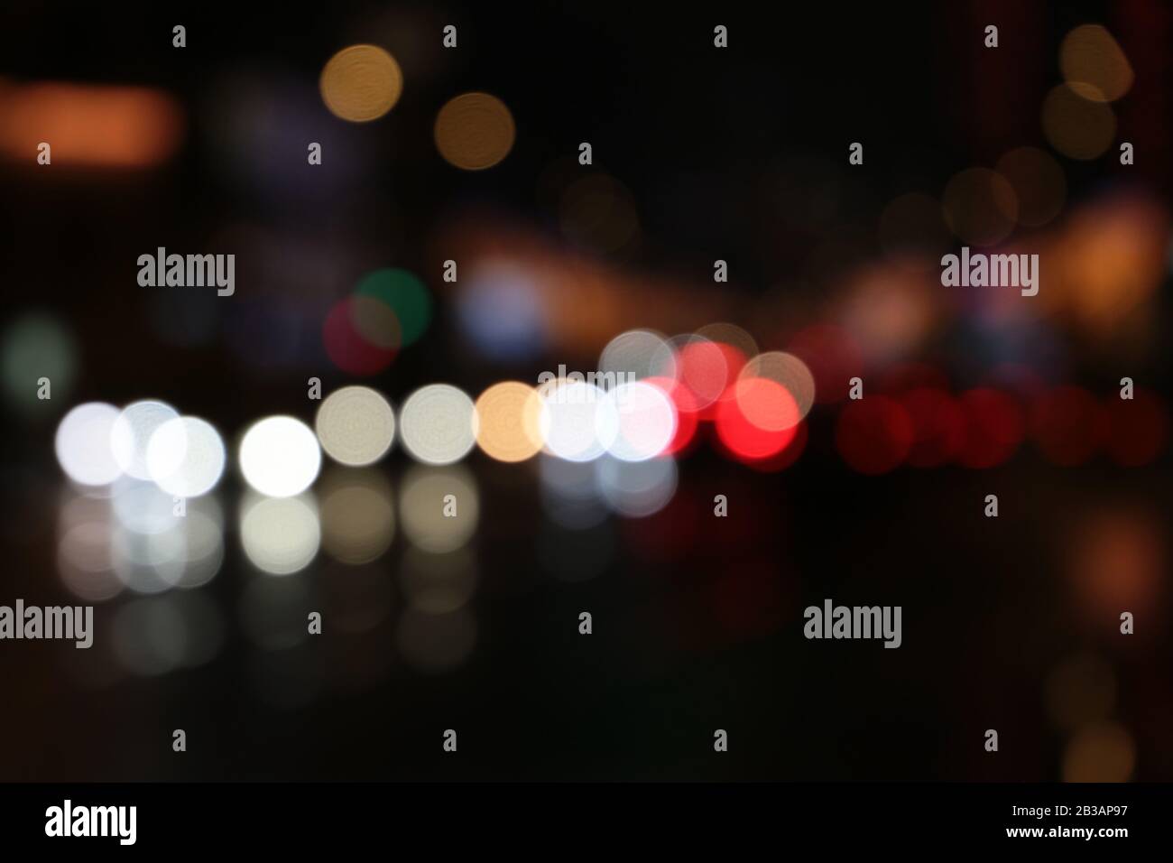 Lumières floues des phares de voiture sur la route de nuit de la ville pendant la pluie. Arrière-plan abstrait coloré Banque D'Images