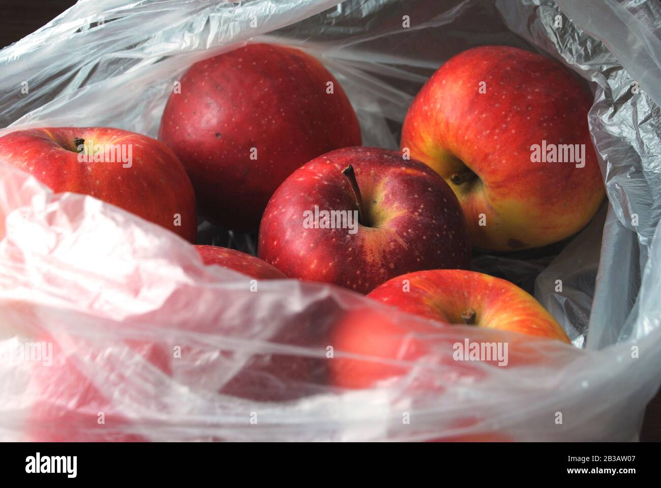 Pommes rouges biologiques naturelles fraîches dans un sac blanc transparent en plastique polyéthylène du supermarché Banque D'Images