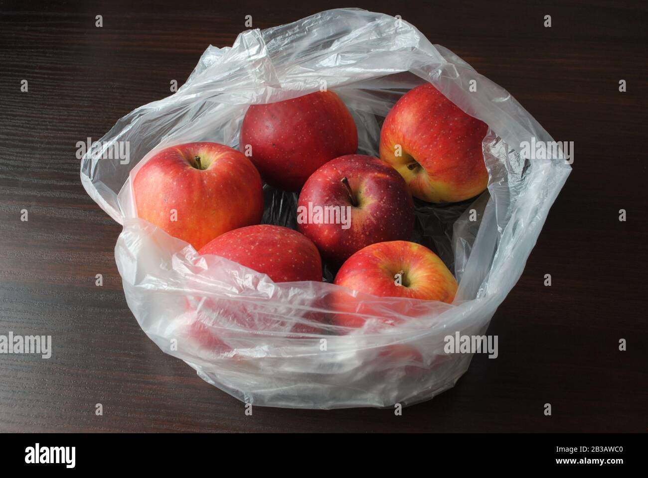 Pommes rouges biologiques naturelles fraîches dans un sac blanc transparent en plastique polyéthylène du supermarché Banque D'Images