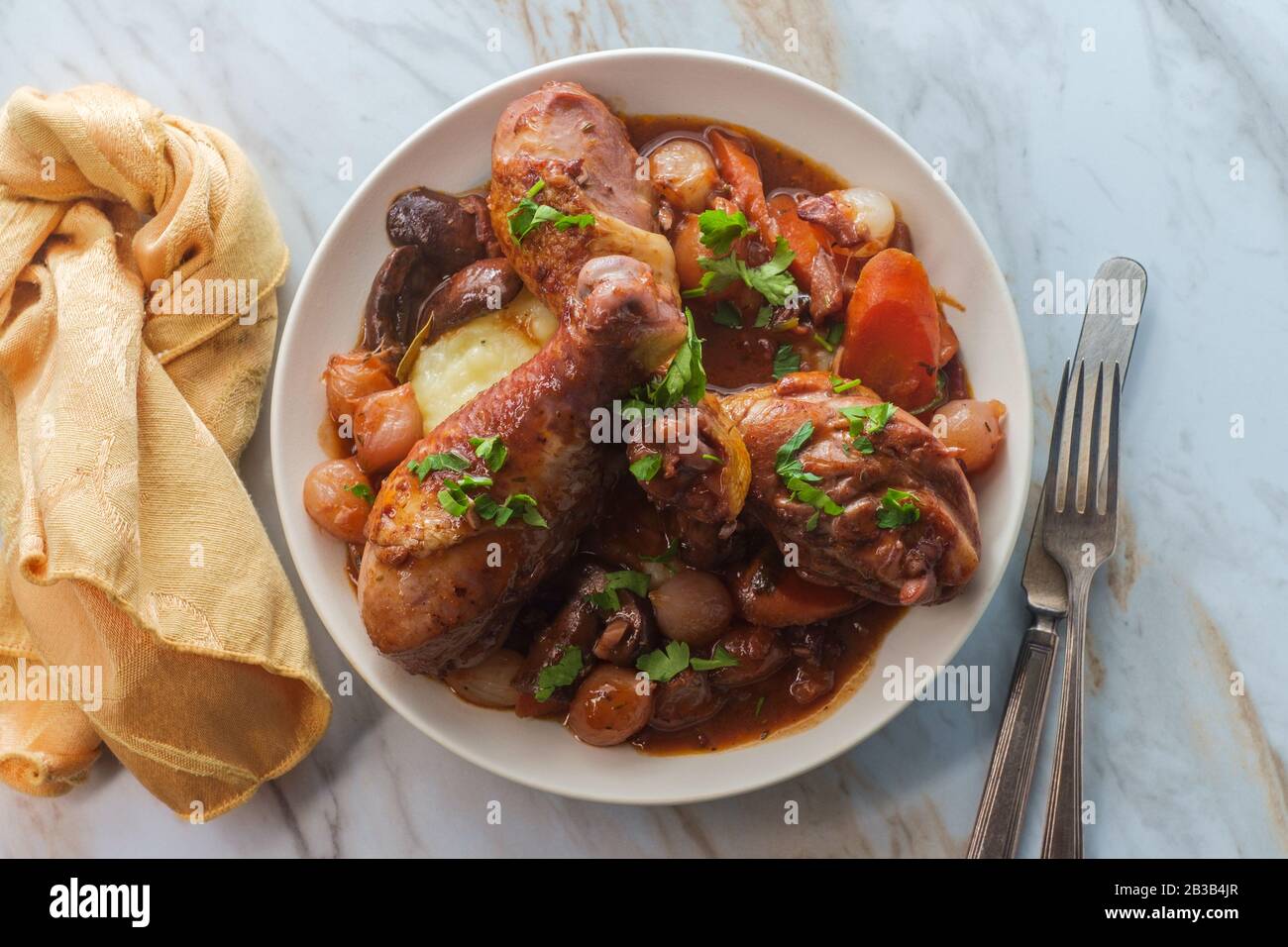 Cuisine française Coq au vin ragoût avec des champignons crimini oignons perlés et carottes dans une sauce au brandy au vin rouge servie sur une purée de pommes de terre Banque D'Images