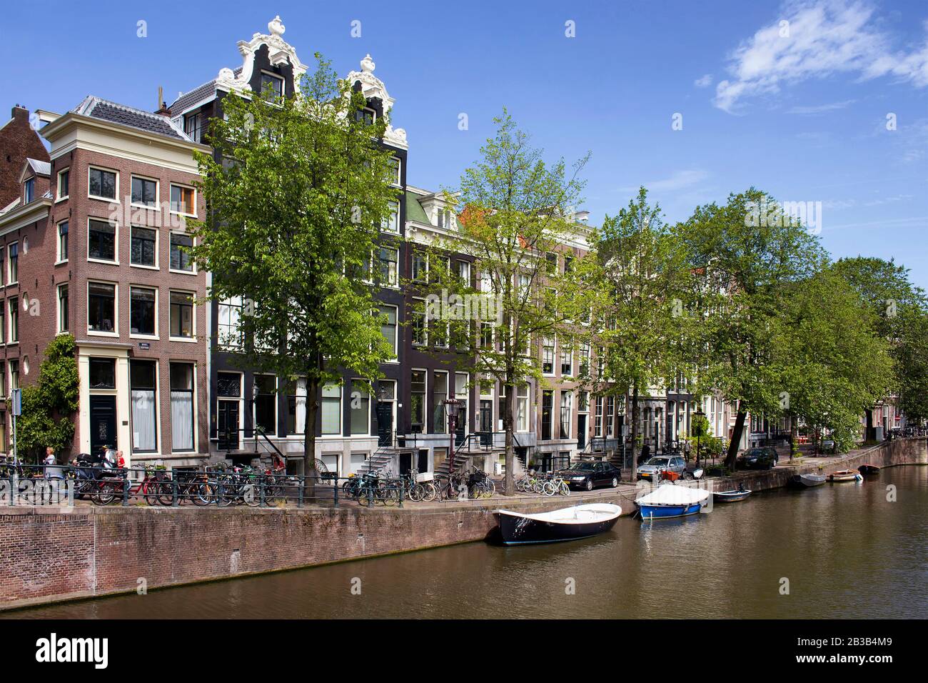 Vue sur le canal, les bateaux garés, les vélos et les voitures et les bâtiments historiques et traditionnels montrant le style architectural néerlandais à Amsterdam. C'est ensoleillé Banque D'Images