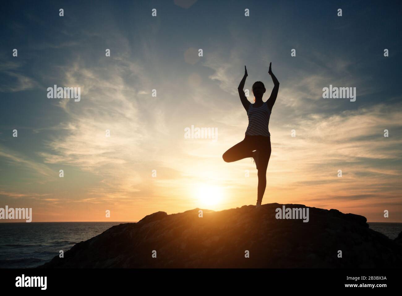 Silhouette d'une femme de yoga de fitness, exercices matinaux sur le coucher du soleil de la plage de la mer. Banque D'Images