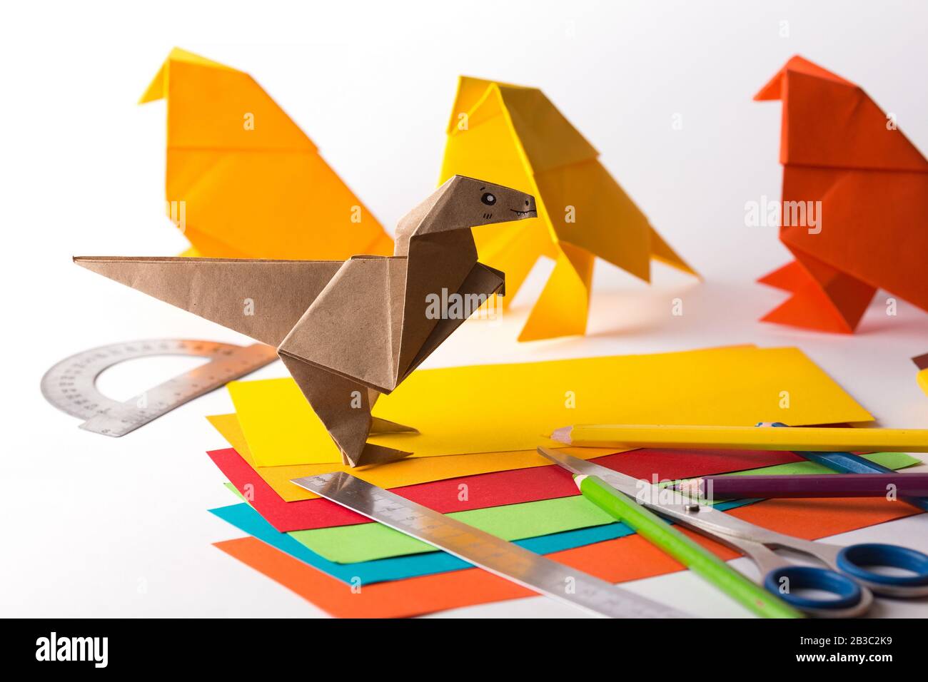 oiseau origami et dinosaure en papier de couleur. papier, règle, crayons, couteau. passe-temps intéressant Banque D'Images