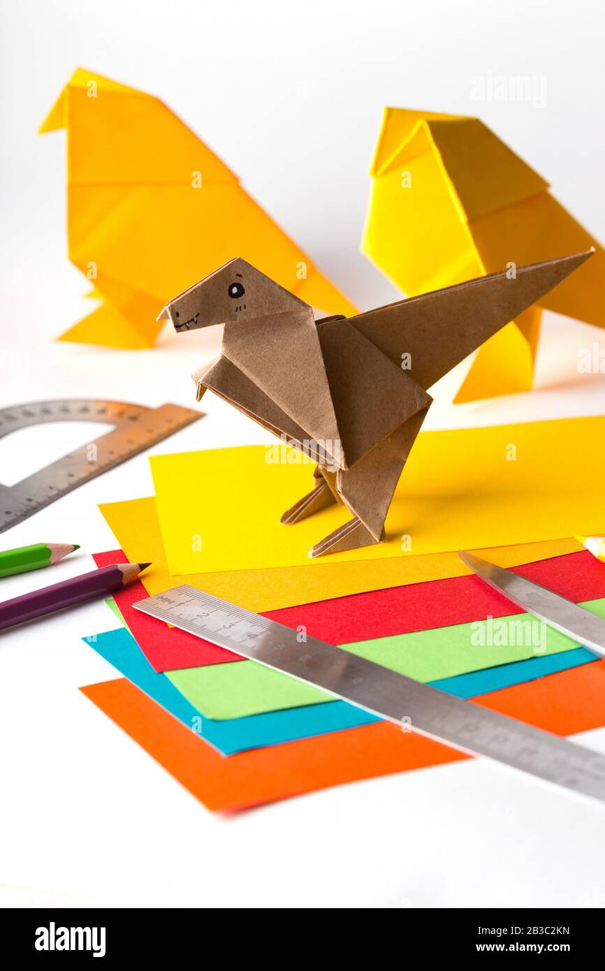 oiseau origami et dinosaure en papier de couleur. papier, règle, crayons, couteau. passe-temps intéressant Banque D'Images