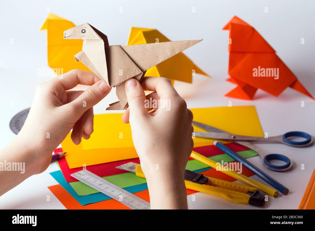 fille fait origami dinosaure de papier de couleur. papier, règle, crayons, couteau. passe-temps intéressant Banque D'Images