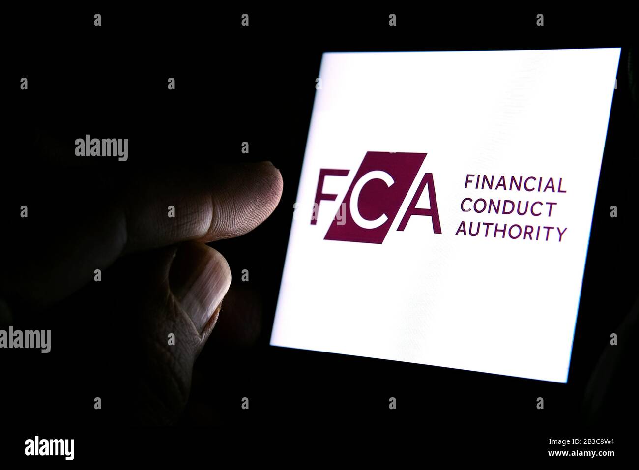 Logo FCA Financial Conduct Authority sur le smartphone et doigt pointant vers lui dans la pièce sombre. Concept. FCA est un organisme de réglementation financière au Royaume-Uni Banque D'Images