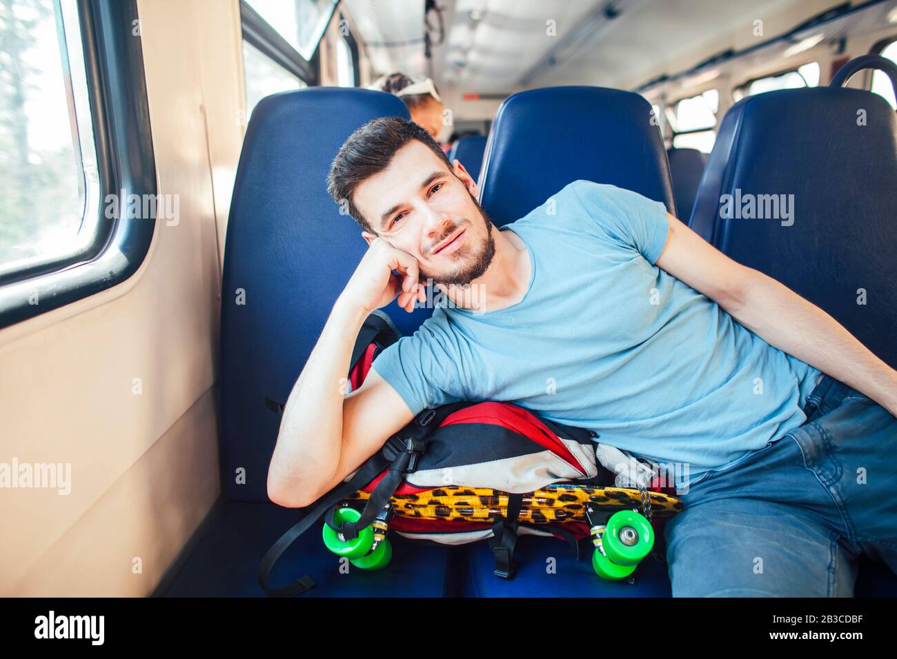 Très jolie hipster moderne guy voyageur sur train avec skateboard seul, le mode de vie des gens vacances concept Banque D'Images