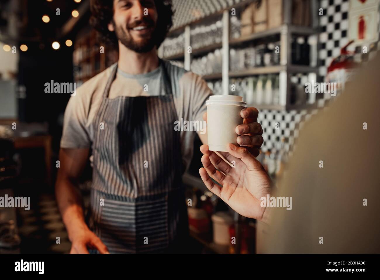 Serveur servant une tasse de café froid au client au comptoir dans le café Banque D'Images