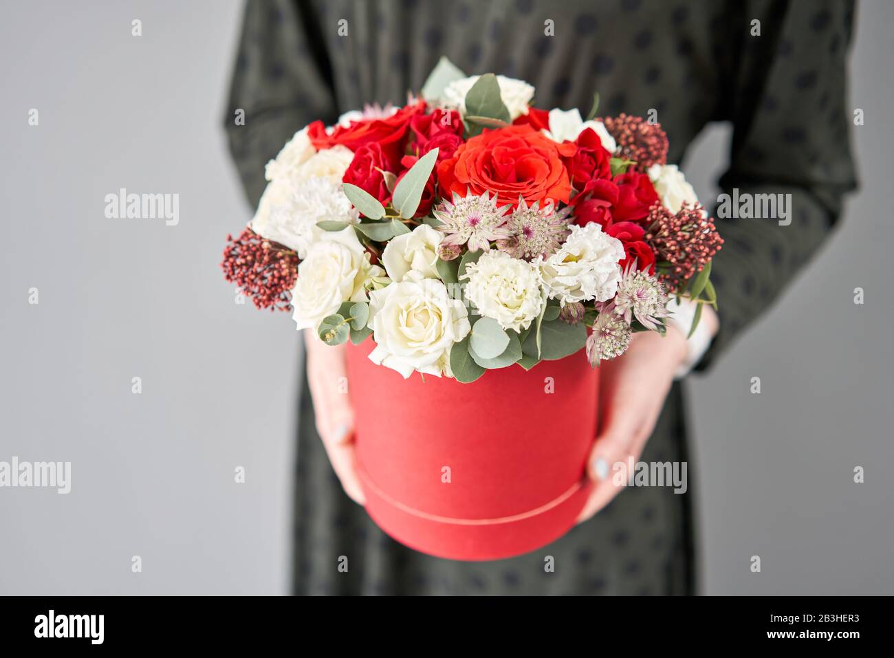 Bouquet floral rouge et blanc dans une boîte ronde. Boutique européenne de fleurs. Bouquet de belles fleurs mixtes dans la main de la femme. Banque D'Images