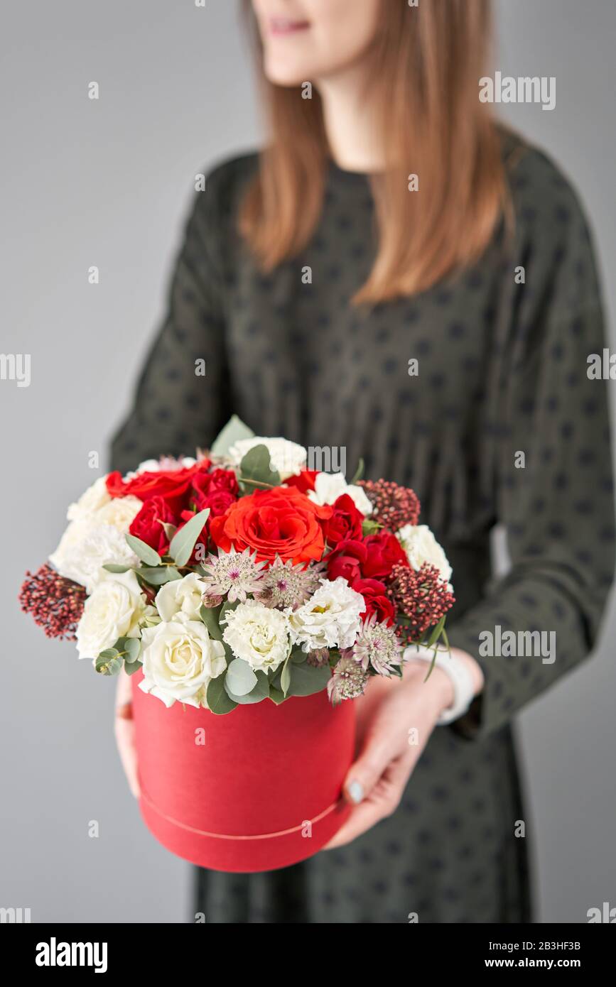 Bouquet floral rouge et blanc dans une boîte ronde. Boutique européenne de fleurs. Bouquet de belles fleurs mixtes dans la main de la femme. Banque D'Images