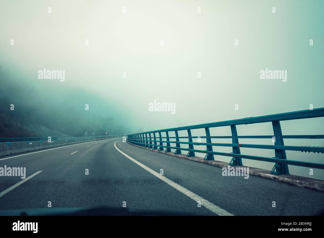 Vue du dépassement à travers le pare-brise. Magnifique paysage matinal misty avec une autoroute, un pont, et un ciel nuageux spectaculaire. Asturies, Espagne Banque D'Images