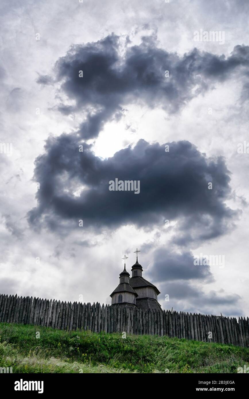 Ancienne église en bois derrière une vieille clôture contre un ciel dramatique Banque D'Images