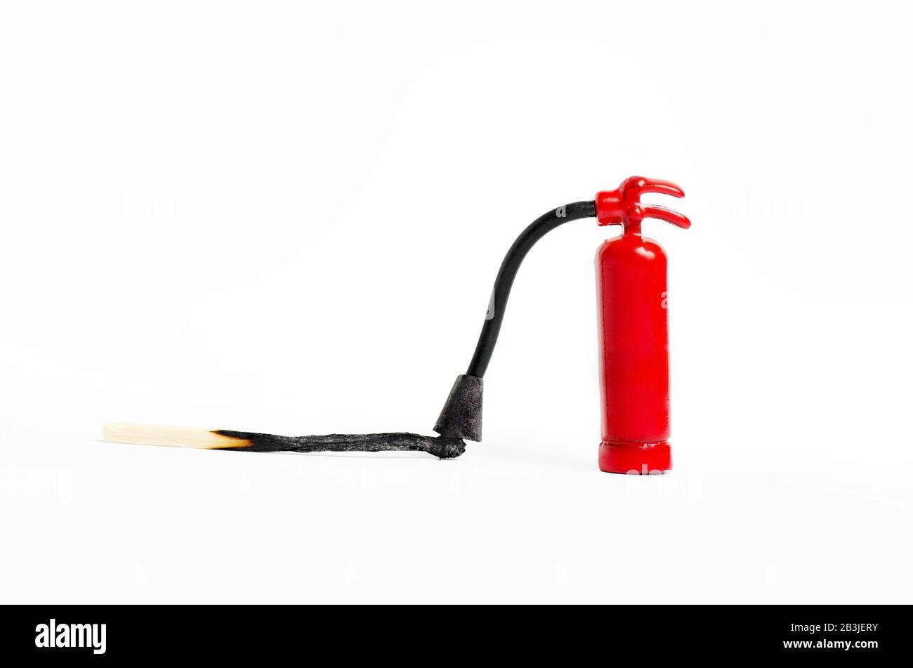Extincteur miniature proche d'une correspondance brûlée sur fond blanc, macro shot Banque D'Images