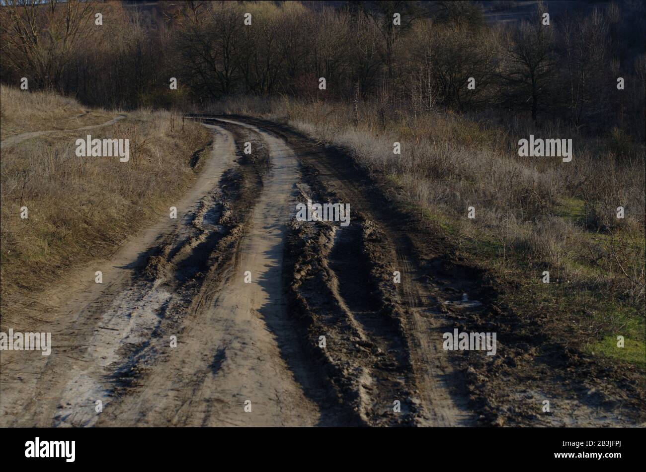 Mauvaise route brouillée au printemps. Gros plan de la sale route de campagne après la fonte de la neige ou la pluie. Chemin boueux avec des traces de pneus parmi les collines Banque D'Images