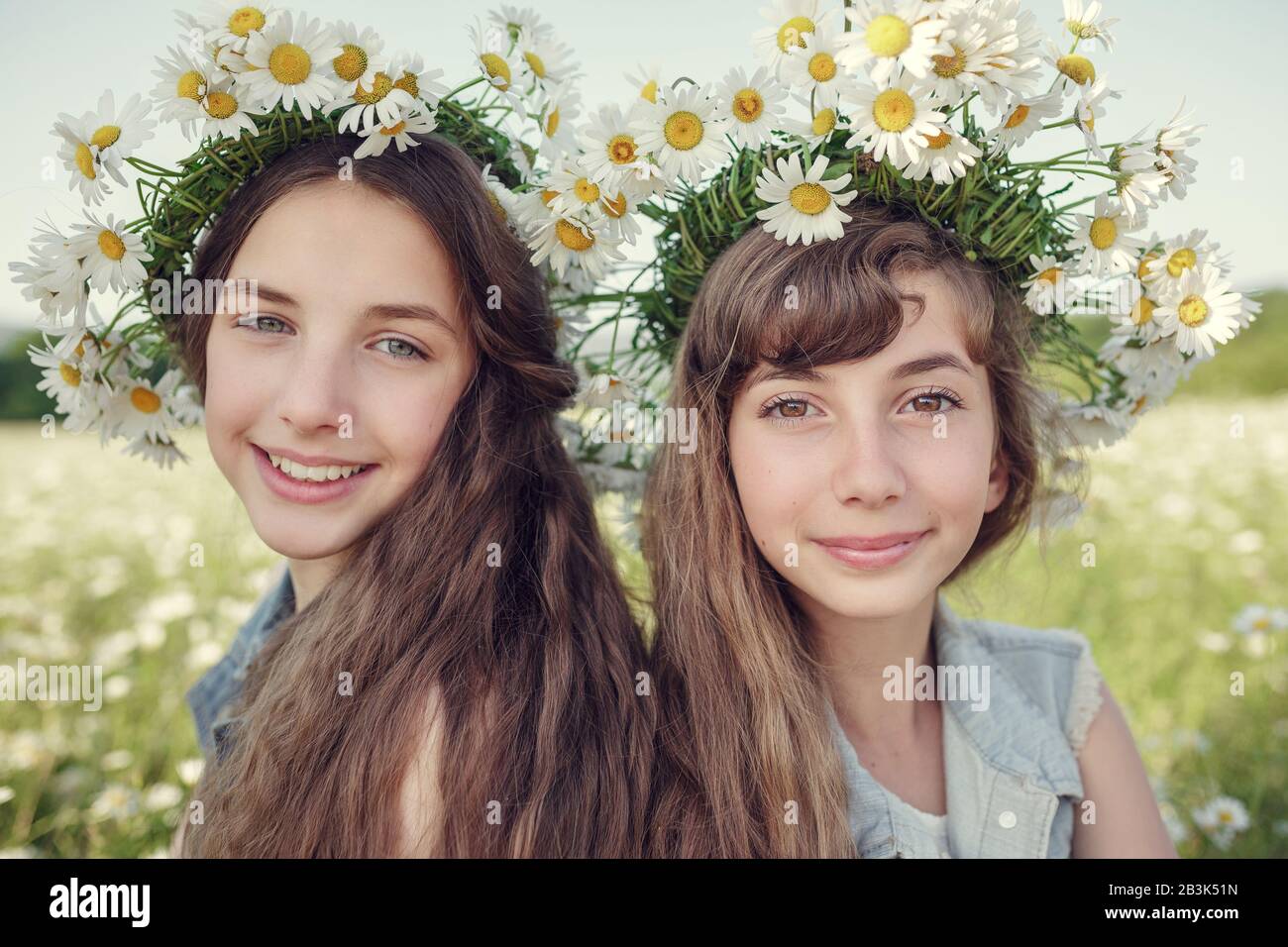 Petite fille dans un champ de fleurs de Marguerite. Les filles dans une couronne de daisies blanches, le concept et l'idée d'une enfance heureuse Banque D'Images