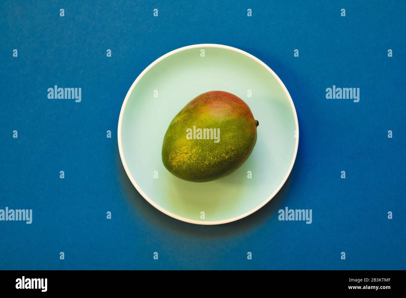 Fruits à la mangue mûre et frais naturels en assiette sur fond bleu. Pose plate. Banque D'Images