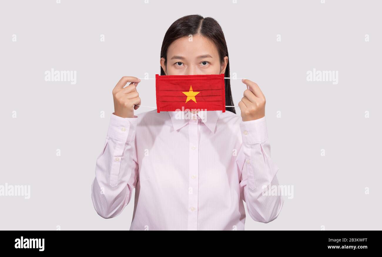 Une femme asiatique portant un masque facial hygiénique peignant le drapeau du Vietnam pour se protéger du Coronavirus 2019 (COVID-19) cas d'épidémie d'infection, le virus o Banque D'Images