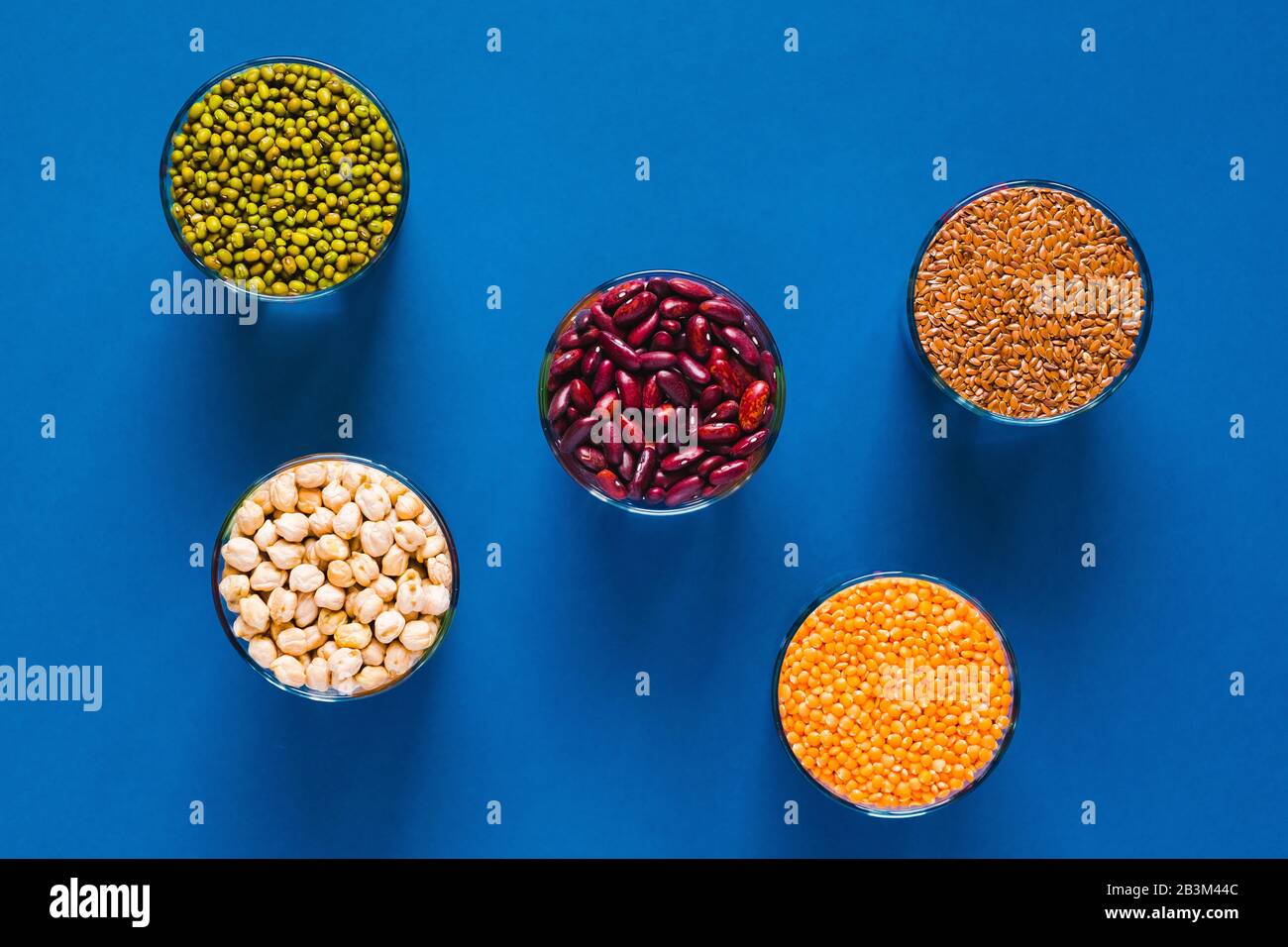 Ensemble de différentes céréales et légumineuses dans un bol en verre sur une table noire, vue du dessus. Concept d'alimentation saine. Banque D'Images