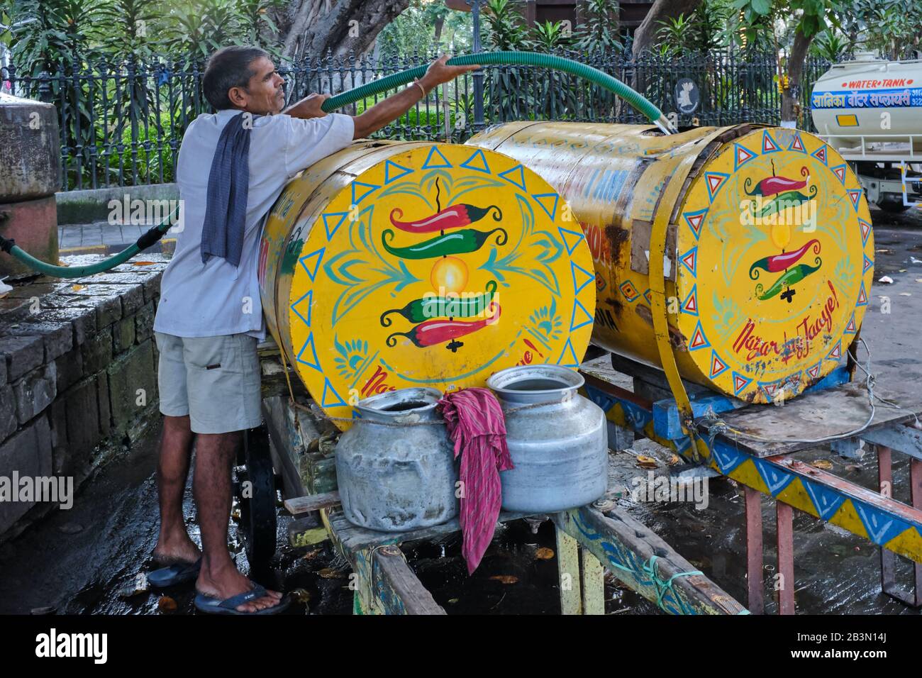 Un extracteur de chariot à main remplissant des réservoirs avec de l'eau d'un puits à Horniman Circle, fort, Mumbai, Inde, pour livrer aux bureaux et maisons sans eau courante Banque D'Images