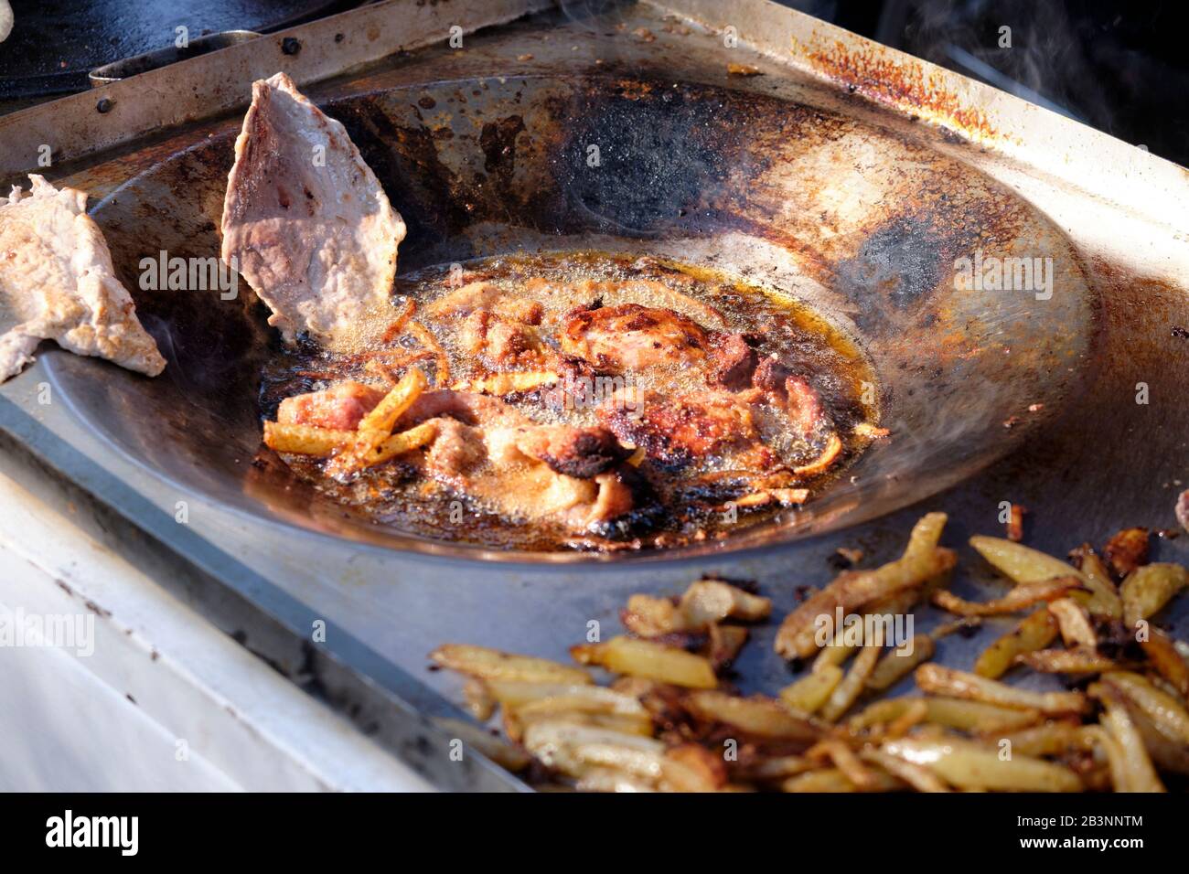 Une voiturette de cuisine mexicaine à l'extérieur fait frire diverses viandes et frites dans une poêle lors d'un salon du Carnaval Banque D'Images