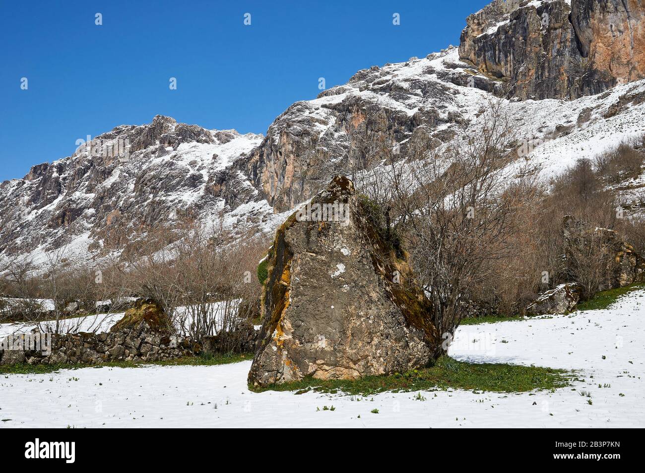 Big rock dans un champ enneigé dans le PR.AS-15 sentier de randonnée avec des montagnes enneigées en arrière-plan (Valle del Lago, Somiedo Natural Park, Asturies, Espagne) Banque D'Images