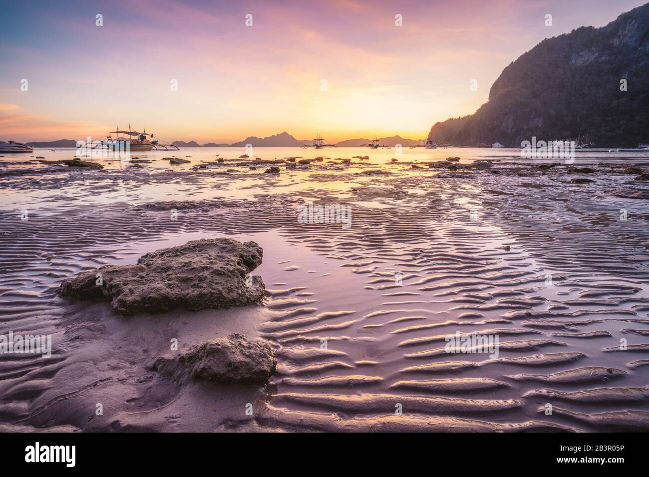 Plage De Corong, El Nido, Philippines. Coucher de soleil sur la plage tropicale. Réflexions du soleil à l'heure d'or. Les îles de la chaîne de montagnes à l'horizon Banque D'Images