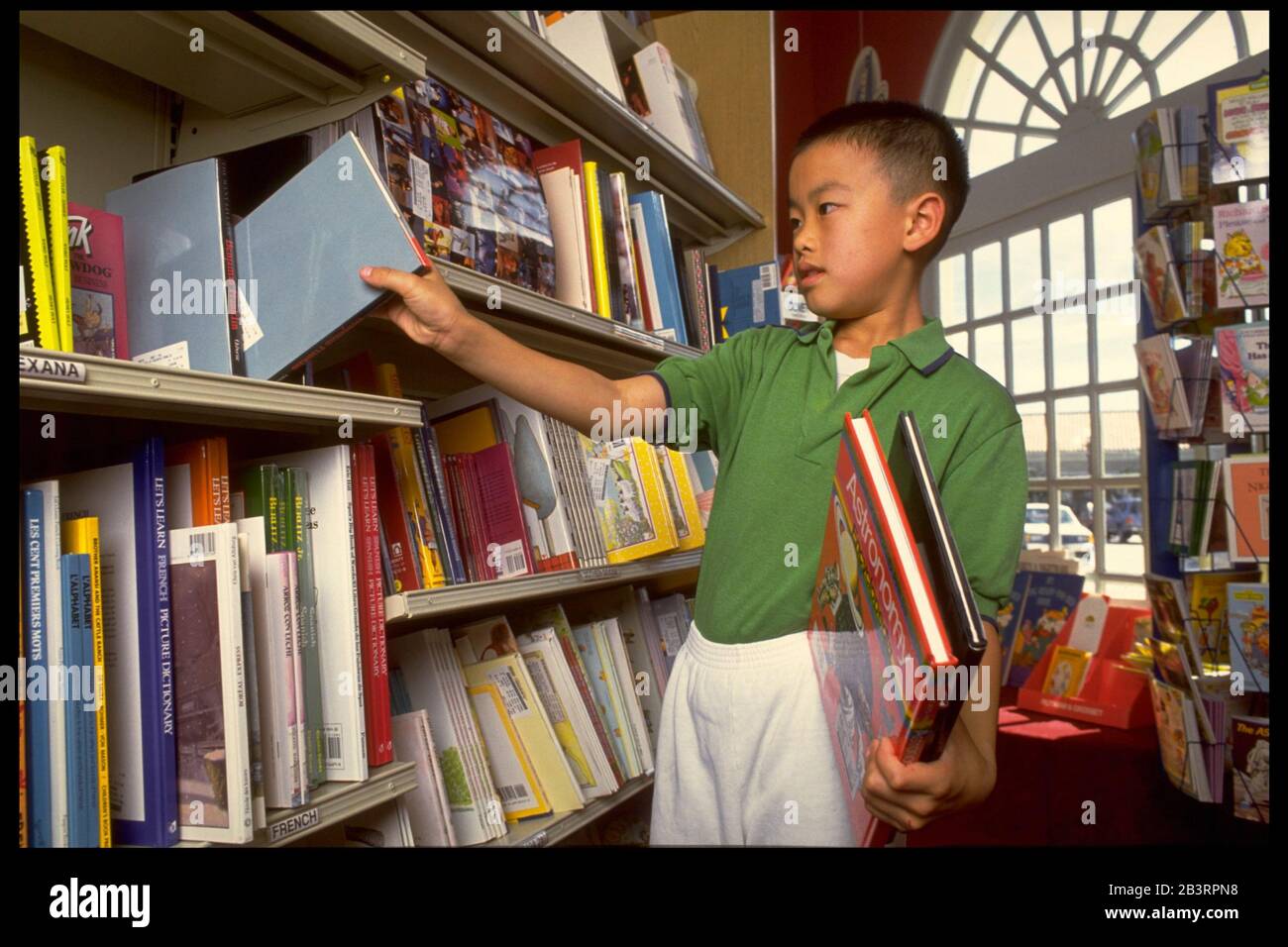 Austin Texas USA, 1991:Vietnamien-américain 5th grade garçon regarde les livres dans le département des enfants dans une librairie locale.M. EV-005 ©Bob Daemmrich Banque D'Images