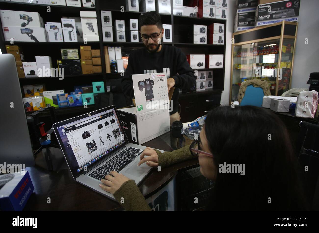 Naplouse. 5 mars 2020. Une femme palestinienne fait des boutiques en ligne  sur le site Web d'Amazon via un ordinateur portable dans un magasin de la  ville de Naplouse, en Cisjordanie, le