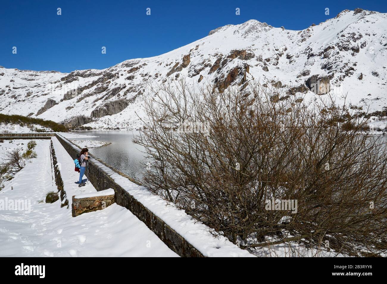 Randonneur féminin dans le lac de montagne du Lago del Valle et pics de montagne escarpés en une journée ensoleillée (Valle del Lago, Somiedo Natural Park, Asturies, Espagne) Banque D'Images