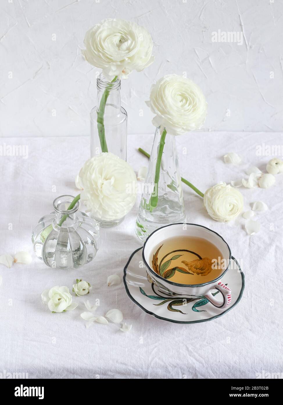 Une tasse de thé et de fleurs de ranunculus blanches sur une table blanche Banque D'Images