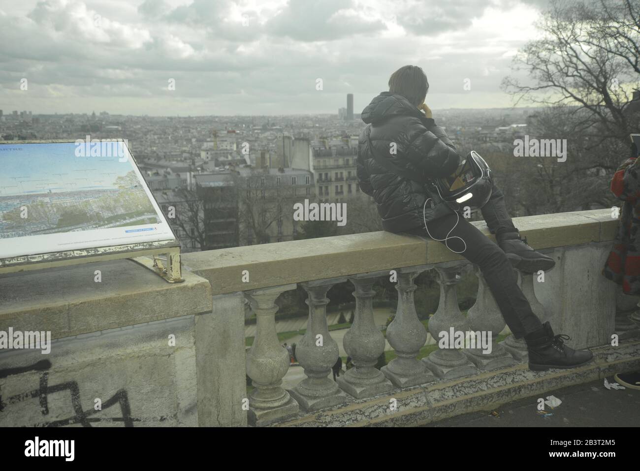 Jeune homme assis sur un mur donnant sur Paris, pasakdek Banque D'Images