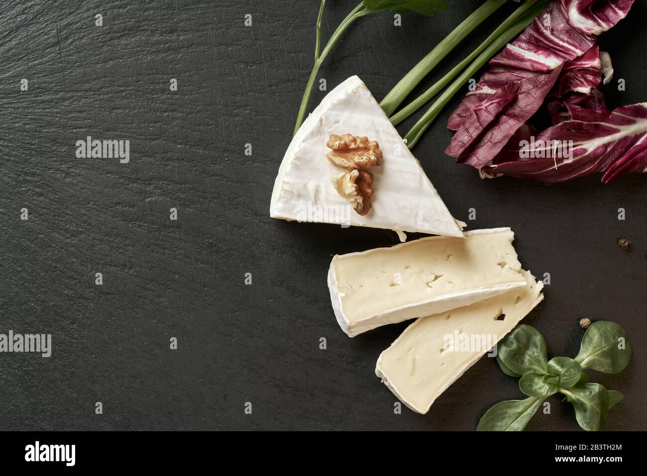 Délicieux fromage brie sur fond noir. Type de fromage Brie. Camembert. Du fromage Brie frais et une tranche sur le plateau en pierre. Italien, fromage français. Banque D'Images