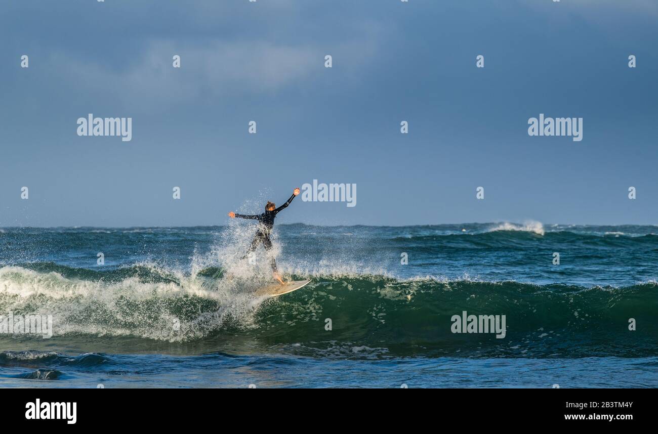 Mossel Bay, Afrique Du Sud. Surfer sur les vagues. Surfeur de la vague de équitation avec l'arc-en-ciel sur fond de ciel de tempête. Banque D'Images
