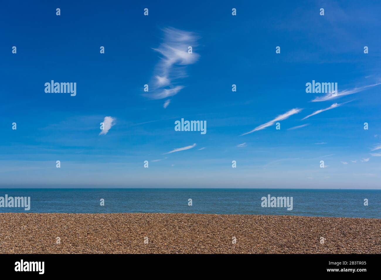 Plage vide montrant ciel bleu, mer et bardeaux. Aldeburgh. Suffolk. ROYAUME-UNI Banque D'Images