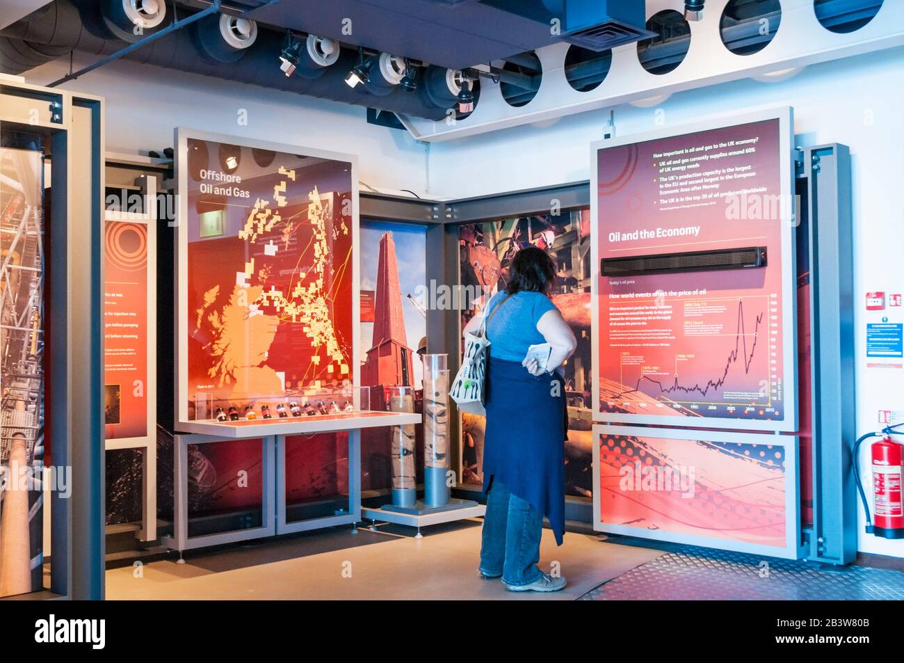 Une femme regardant une exposition sur l'industrie pétrolière et gazière en mer au Musée maritime d'Aberdeen. Banque D'Images