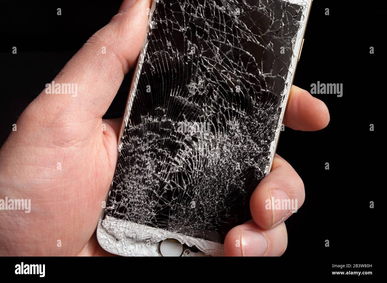 Smartphone moderne avec écran cassé fortement chez les hommes Main sur fond noir. Banque D'Images