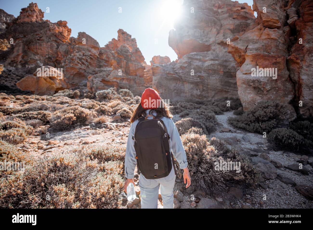 Jeune voyageur féminin marchant sur le terrain rocheux entre d'énormes roches d'origine volcanique pendant une journée ensoleillée. Voyager sur l'île de Tenerife, Espagne Banque D'Images