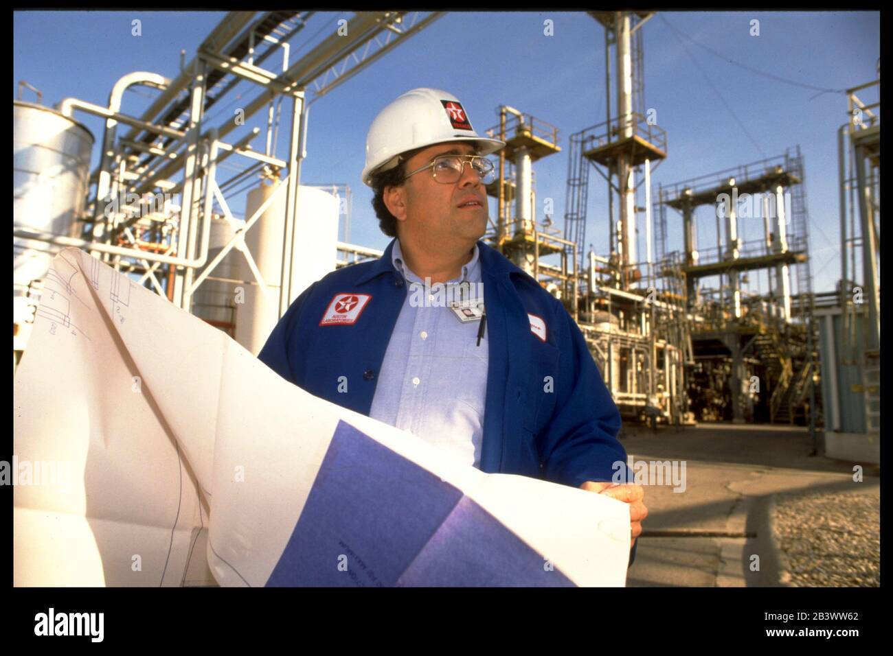 Austin Texas USA: Un ingénieur chimique hispanique de sexe masculin examine les plans à la raffinerie Texaco.©Bob Daemmrich Banque D'Images