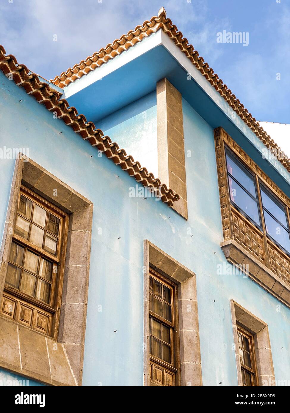 Fragment architectural de l'ancien bâtiment lumineux de style colonial avec fenêtres et décor simple. Image réalisée sur le téléphone portable Banque D'Images