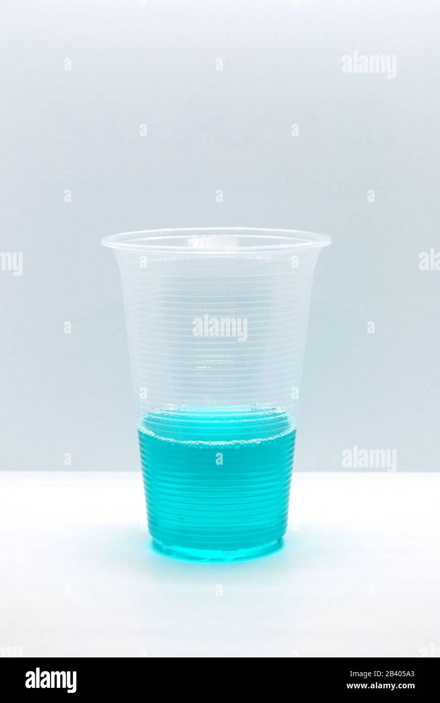 Tasse en plastique avec liquide de couleur bleu turc brillant sur fond blanc Banque D'Images