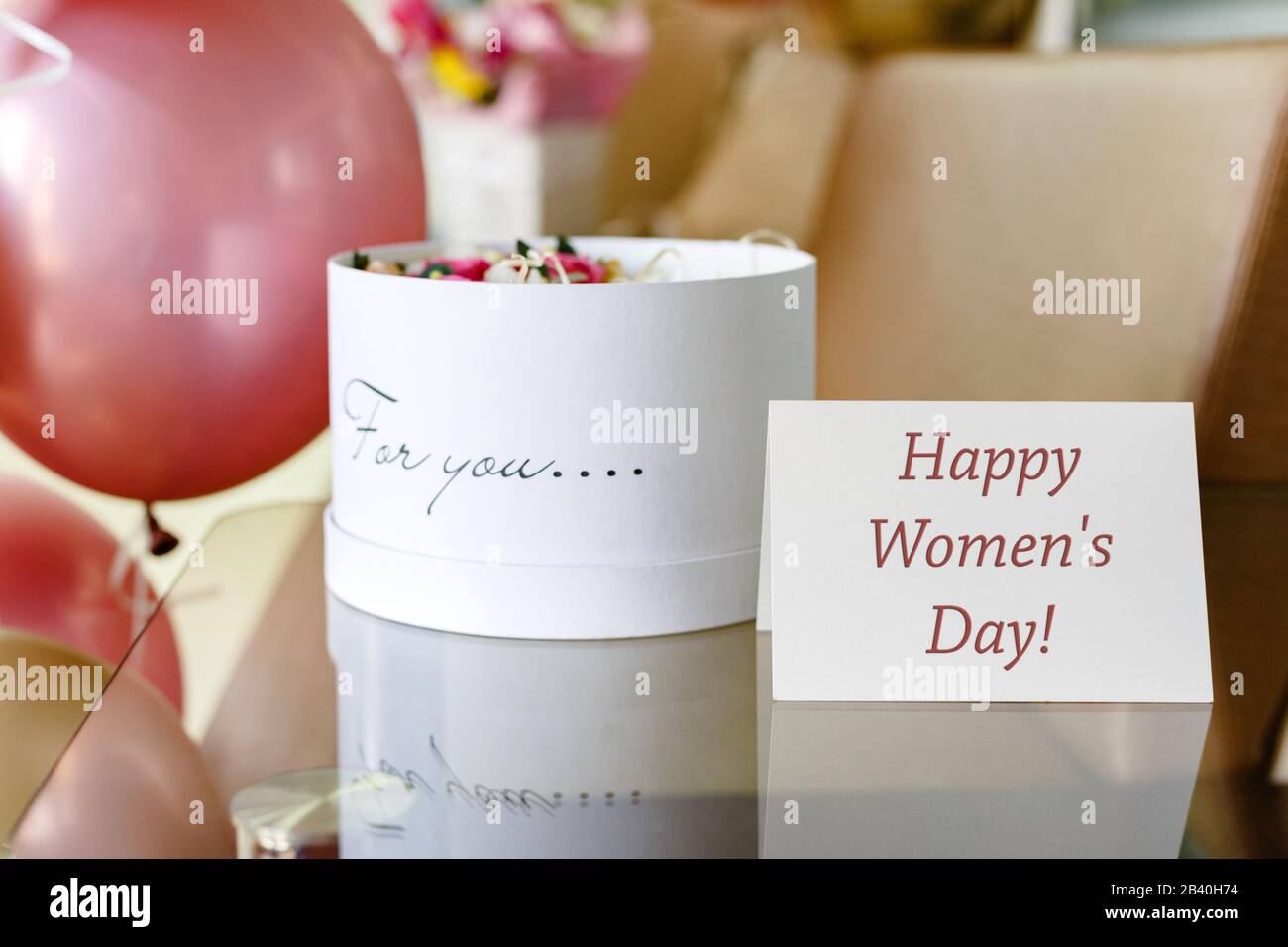 Happy Womens Day texte sur la carte-cadeau dans la boîte à fleurs près des roses festives et des ballons d'or. Carte de vœux pour les femmes le 8 mars, Journée internationale de la femme Banque D'Images