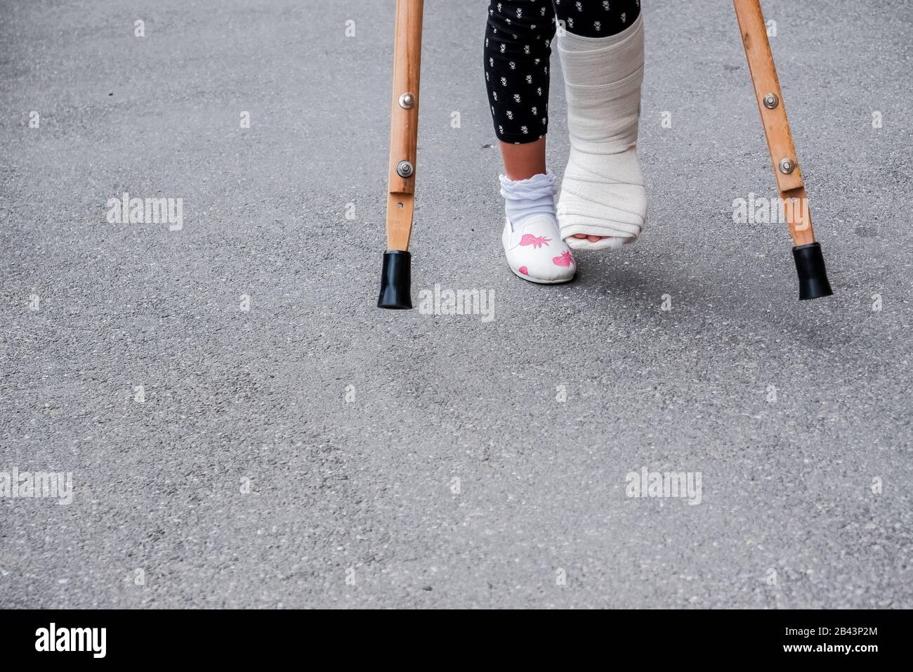 Enfant avec une jambe cassée est sur des béquilles dans la rue. Photo conceptuelle représentant