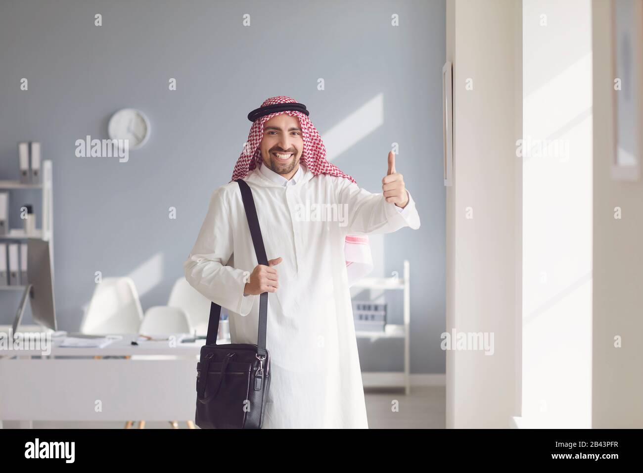 Un homme arabe heureux a levé le pouce dans un bureau blanc Banque D'Images